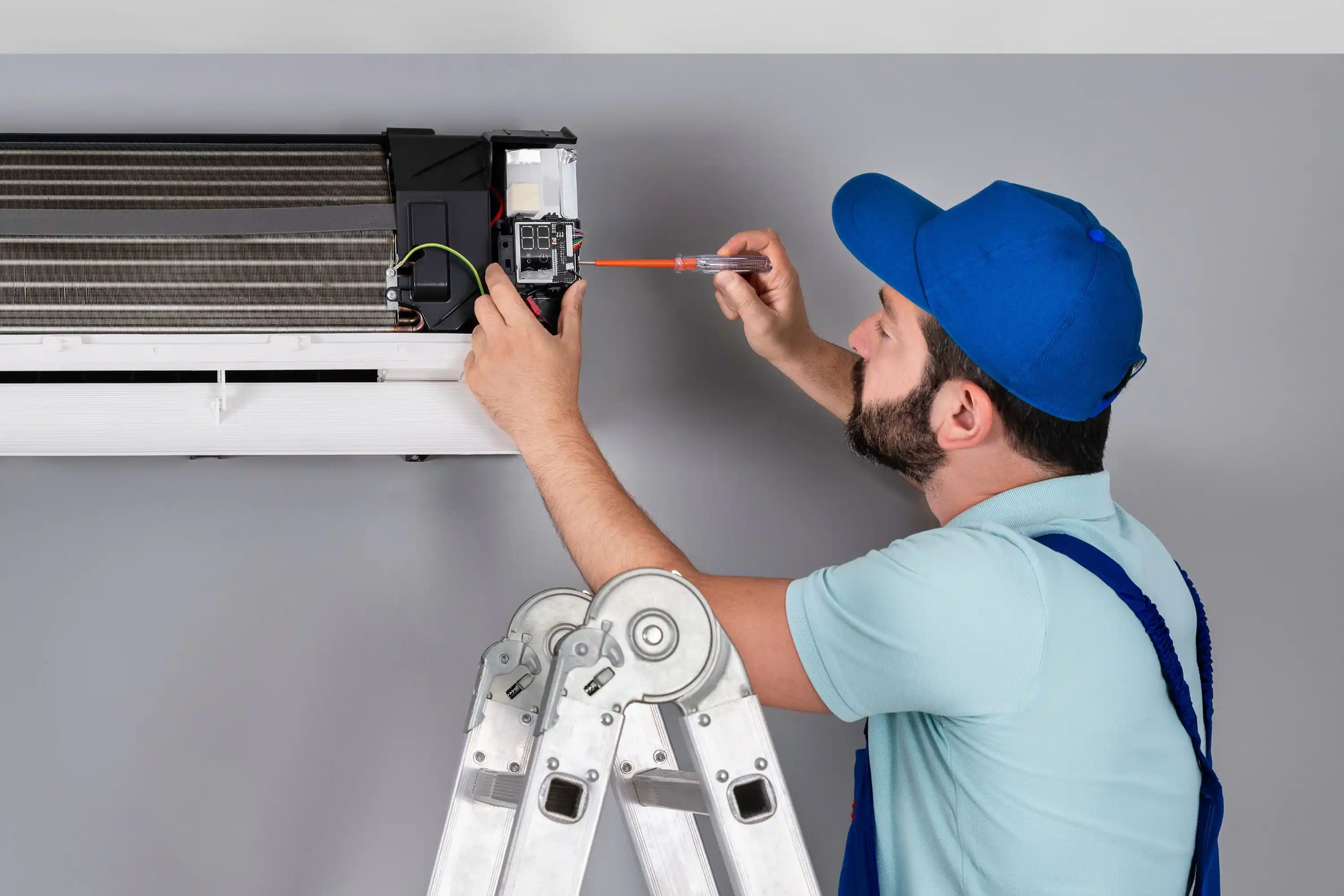 A man making repairs to an air conditioner unit.