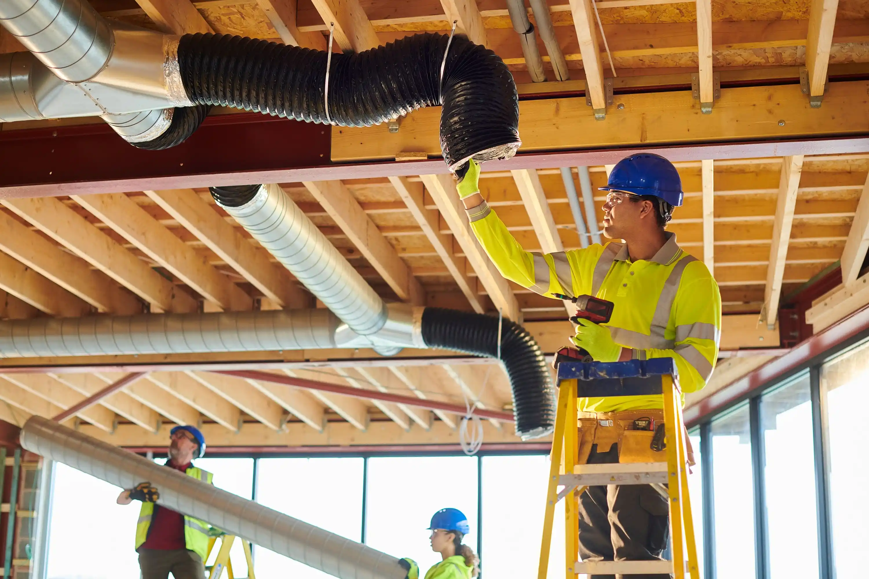 A man installing air conditioner piping in a construction site.