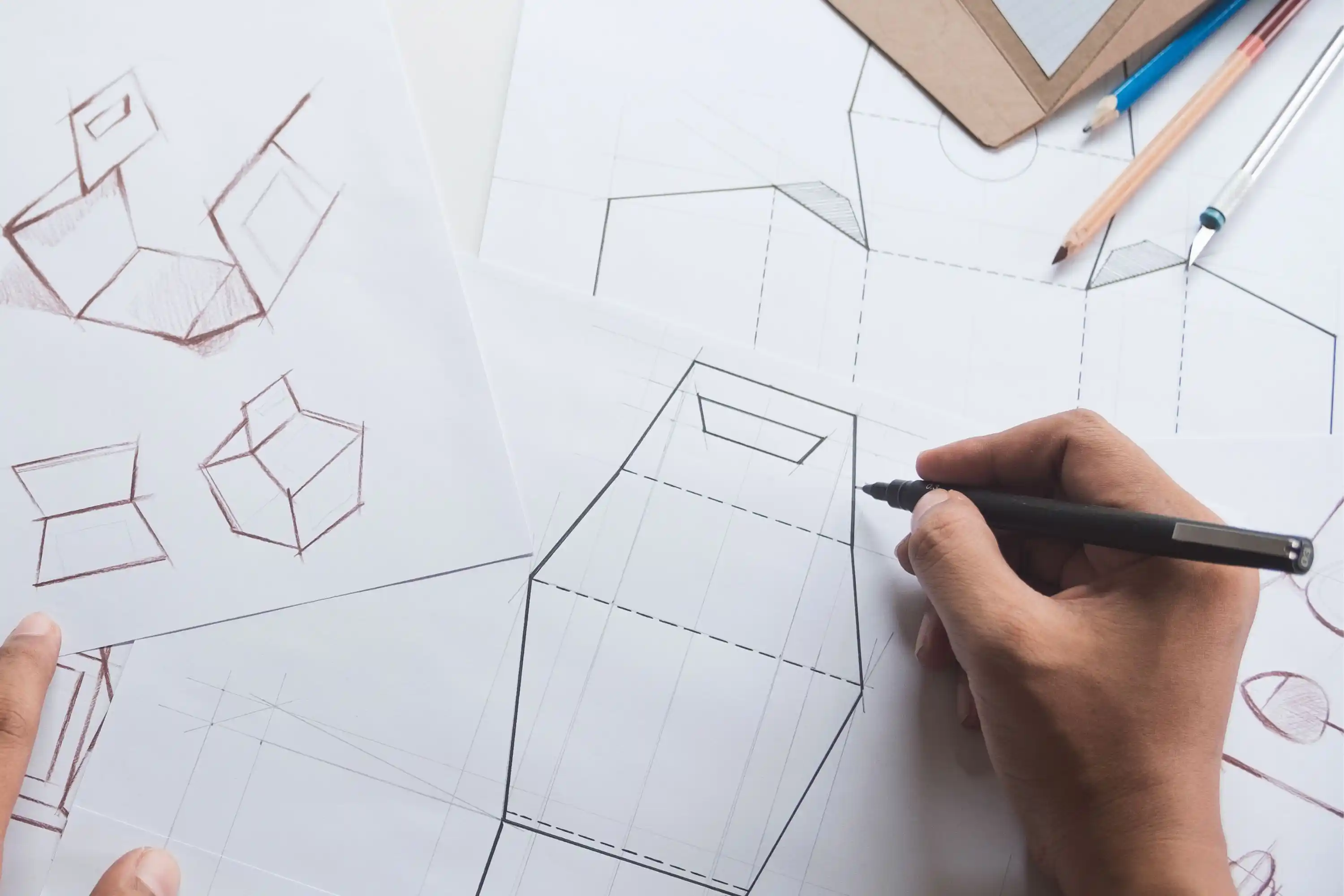 A hand drawing schematic designs on a large piece of paper.